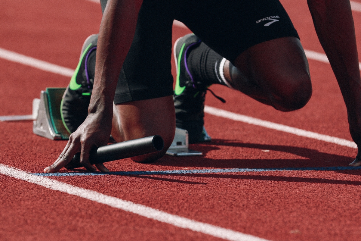 A runner utilizing CBD for enhanced athletic performance crouching down on a track.