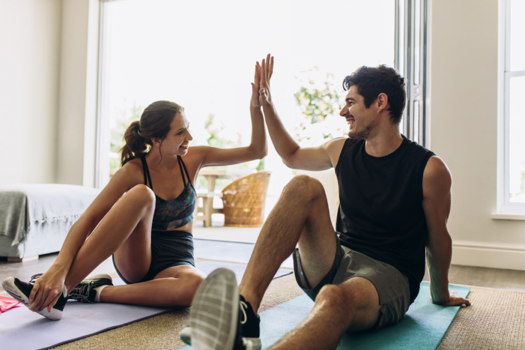 Young couple giving each other a high five in the living room after a workout.