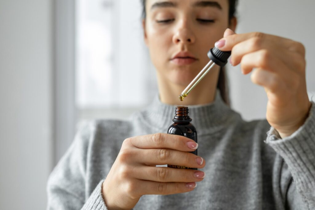 A woman is holding a bottle of CBD oil, known for its potential benefits in alleviating sinus issues.