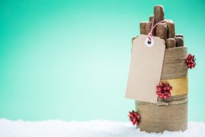 A box of cigars, a perfect stocking stuffer idea for men, delicately placed in the snow with a tag on it.