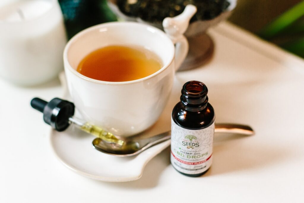 A bottle of CBD oil next to a cup of tea, providing a relaxing experience while promoting CBD education.