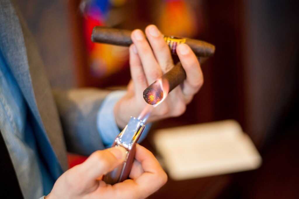 A man is holding a cigar, showcasing potential gift ideas for cigar lovers.