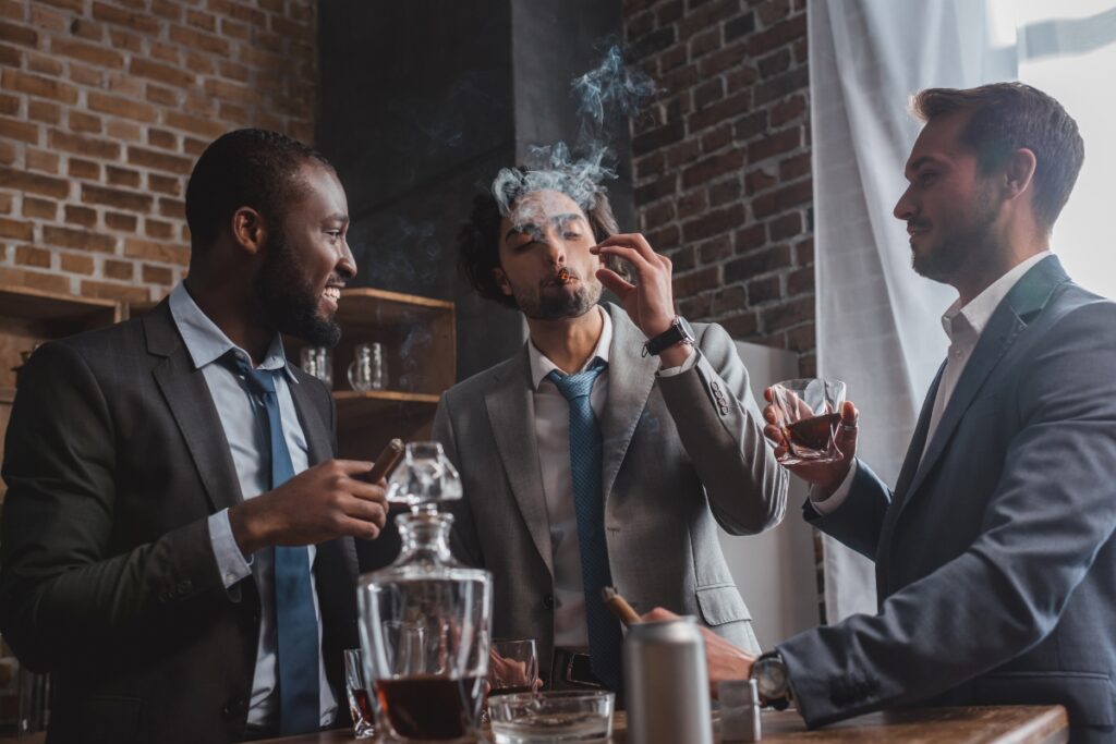 Three businessmen enjoying cigar gift ideas in a bar.