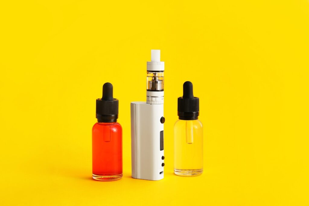 Three e-liquid bottles and a vape starter kit on a yellow background.