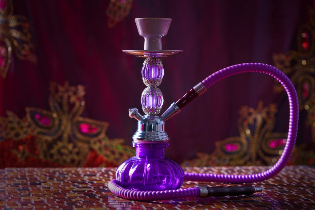 A purple hookah with various flavors on a wooden table.