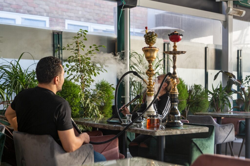 A man and woman smoking different hookah flavors in a restaurant.