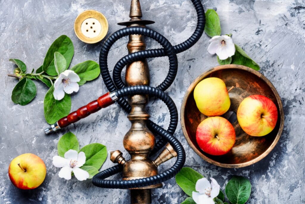 A hookah with apple flavors and flowers on a gray background.