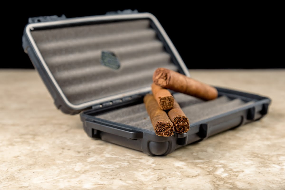 Three cigars rest inside an open, black cigar case on a marble surface, awaiting the discerning smoking enthusiast.