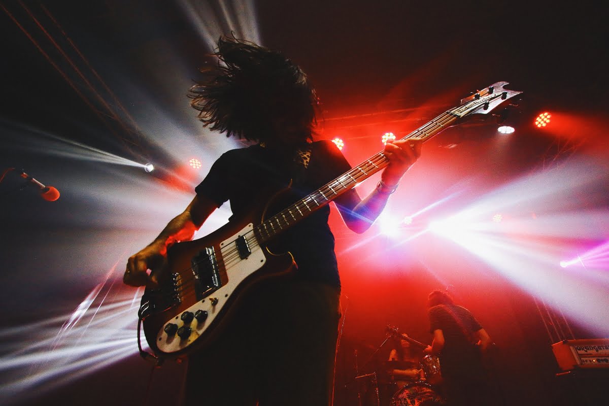 A musician plays an electric guitar on stage with vibrant lighting and dramatic effects, creating an atmosphere reminiscent of a smoking session during a live performance.