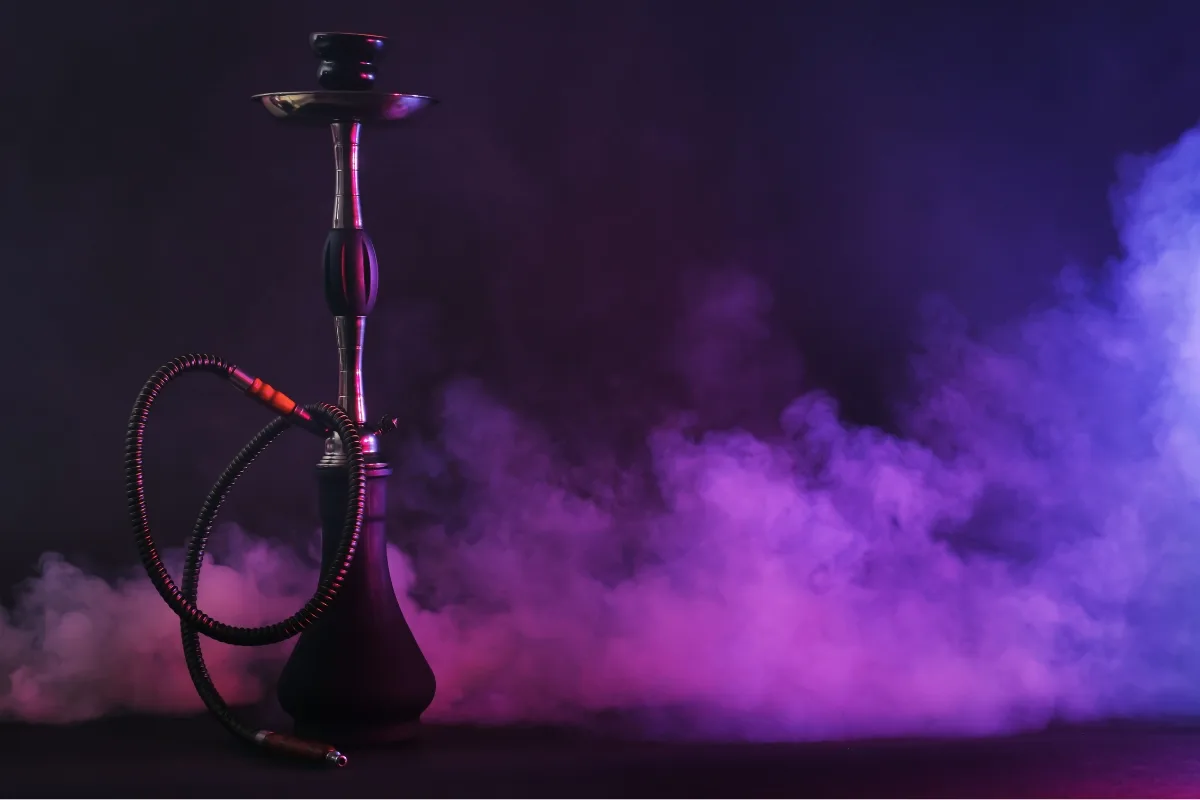 A hookah stands proudly against a swirling backdrop of purple and pink smoke, inviting contemplation on the allure of tradition versus modern alternatives like vaping.